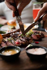 a person cutting meat with a knife on a table at Hollywood Hills Hotel in Los Angeles