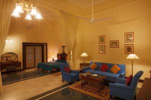 The Lallgarh Palace - A Heritage Hotel في بيكانير: غرفة معيشة مع أريكة وكراسي زرقاء