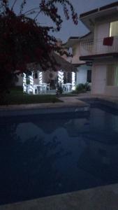 a swimming pool in front of a house at night at Villa kosniin in Tecolutla