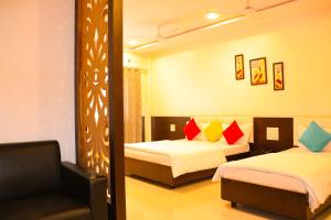 a hotel room with two beds and a mirror at Hotel Neem Tree in Shirdi