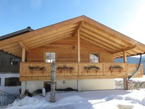 a log home with a large wooden roof at Ferienwohnungen Mooshäusl in Reit im Winkl