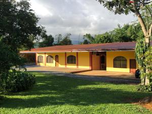 Hospedaje Adrimaran في Palmares: مبنى صغير أصفر مع ساحة عشب