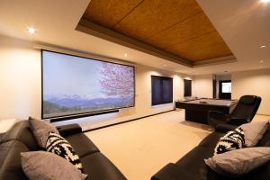 a large screen in a living room with couches and a pool table at THE CASTLE by Hakuba Hotel Group in Hakuba