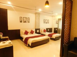 a hotel room with two beds and a television at Hotel Neem Tree in Shirdi