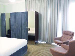 a hotel room with a bed and two chairs and a mirror at Oriental Palace Hotel in Manama