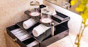 a bathroom shelf with glasses and towels on it at Millennium Harbourview Hotel Xiamen-Near Metro Station & Zhongshan Road in Xiamen