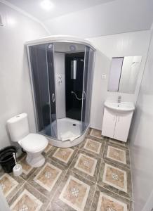 uma casa de banho com um chuveiro, um WC e um lavatório. em Алатау em Shchuchinsk