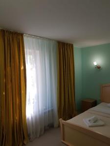 um quarto com uma janela com cortinas e uma cama em Барокко em Bilhorod-Dnistrovsʼkyy