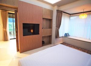 a bedroom with a bed and a flat screen tv at Hideaway in Chiang Mai