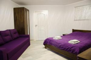 a bedroom with a purple bed and a couch at Ластівчине гніздо in Shaian