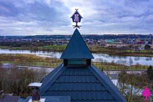 ein Kirchturm mit einem Kreuz darüber in der Unterkunft Very Bad Hootel in Kaunas