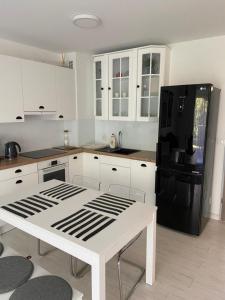 a kitchen with a white table and a black refrigerator at Apartament Biały w Rewalu in Rewal