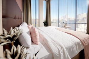 1 dormitorio con cama blanca y ventana grande en Golden Tulip Krasnodar en Krasnodar