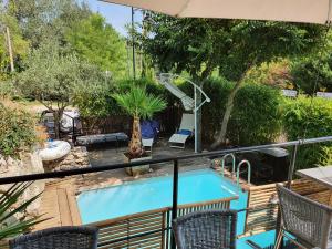 una piscina en un balcón con sillas y sombrilla en Le Tempo, en Entrecasteaux