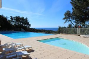 Una piscina con sillas y el océano al fondo. en Très bel appartement T3 avec splendide vue mer, en Les Issambres
