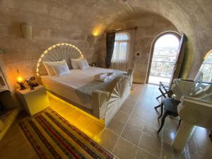 - une chambre en pierre avec un grand lit dans l'établissement Mimi Cappadocia Luxury Cave Hotel, à Uçhisar