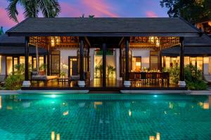 a villa with a swimming pool at night at Anantara Lawana Koh Samui Resort in Chaweng