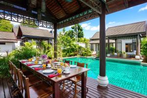 an outdoor dining table in front of a swimming pool at Anantara Lawana Koh Samui Resort in Chaweng