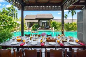 a table set for a meal in front of a pool at Anantara Lawana Koh Samui Resort in Chaweng