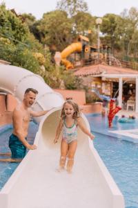 un hombre y una niña en un tobogán en un parque acuático en Camping Sènia Cala Canyelles, en Lloret de Mar