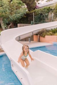 Camping Sènia Cala Canyelles في يوريت دي مار: فتاة صغيرة تنزلق فوق زحليقة في حمام السباحة