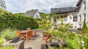 een patio met een tafel en stoelen en een huis bij Pension zum Rothaarsteig Selbstversorgerhaus in Netphen