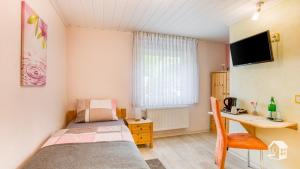 Habitación pequeña con cama, escritorio y ordenador. en Pension zum Rothaarsteig Selbstversorgerhaus, en Netphen