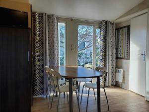 a dining room with a table and chairs and a window at Mobil home récent clim 3ch Camping3* piscine in Argelès-sur-Mer