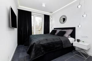 a black and white bedroom with a bed and a window at Apartamenty Słoneczne Tarasy by Renters in Dziwnówek