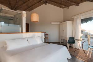 um quarto com uma cama branca e uma janela em MarAdentro Apart Hotel & Suites em Punta Del Diablo