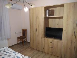 a bedroom with a wooden cabinet with a television in it at Evelin sobe in Bačka Topola