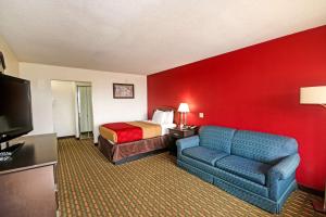 ein Hotelzimmer mit einem Bett, einem Sofa und einem TV in der Unterkunft Econo Lodge Inn And Suites - Pilot Mountain in Pilot Mountain