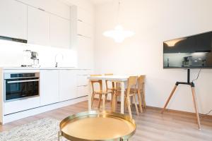 cocina con armarios blancos, mesa y sillas en Apartment City en Oulu