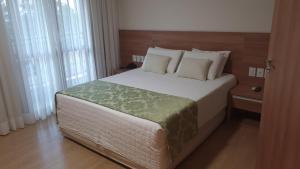 1 dormitorio con 1 cama grande con sábanas y almohadas blancas en Vista Azul Flat Service, en Domingos Martins