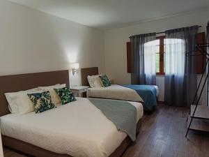 Cette chambre comprend 2 lits et une fenêtre. dans l'établissement Porto D'Abrigo - Alojamento Local, à Sardoal