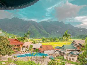 a village with houses and mountains in the background at Mai Chau Green Rice Field Hotel in Mai Châu