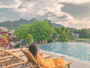 a woman sitting in a chair next to a pool at Mai Chau Green Rice Field Hotel in Mai Châu