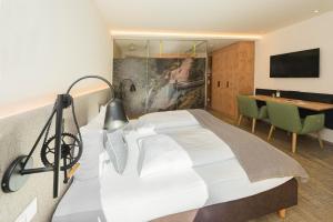a bedroom with a bed and a table and a desk at Lifesport Hotel Hechenmoos in Aurach bei Kitzbuhel