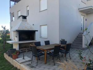 een patio met een tafel en stoelen en een open haard bij Apartment 2 with the swimming pool in Turanj