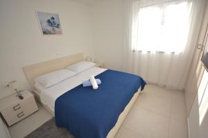 een witte slaapkamer met een bed met een handdoek erop bij Apartment 2 with the swimming pool in Turanj