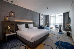 a bedroom with a large bed and a living room at Pullman Sharjah in Sharjah