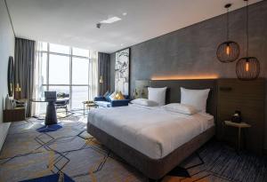 a hotel room with a large bed and a desk at Pullman Sharjah in Sharjah