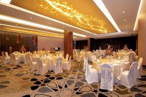 a banquet hall with white tables and white chairs at Pullman Sharjah in Sharjah
