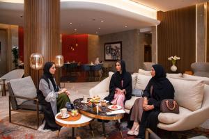 three women sitting on a couch in a lobby at Pullman Sharjah in Sharjah
