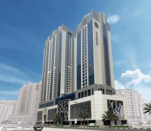 a large tall building with palm trees in front of it at Pullman Sharjah in Sharjah