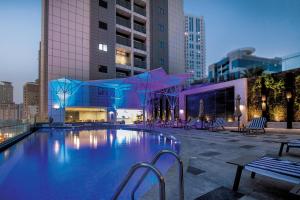 a swimming pool with chairs and a building at Pullman Sharjah in Sharjah