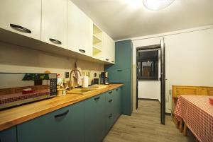 una cocina con armarios azules y blancos y una mesa. en Apartament Diandru, en Slănic-Moldova