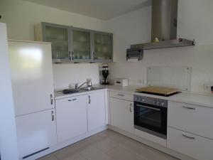 a white kitchen with white cabinets and a sink at Wunderschöne Ferienwohnung ´Mal seh´n`direkt am Nordseedeich in Friedrichskoog-Spitz