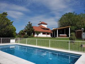a swimming pool in front of a house with a fence at Cabañas Las Pencas in Mina Clavero
