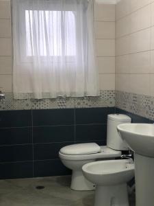 een badkamer met een toilet, een wastafel en een raam bij Appartamento centro in Pogradec